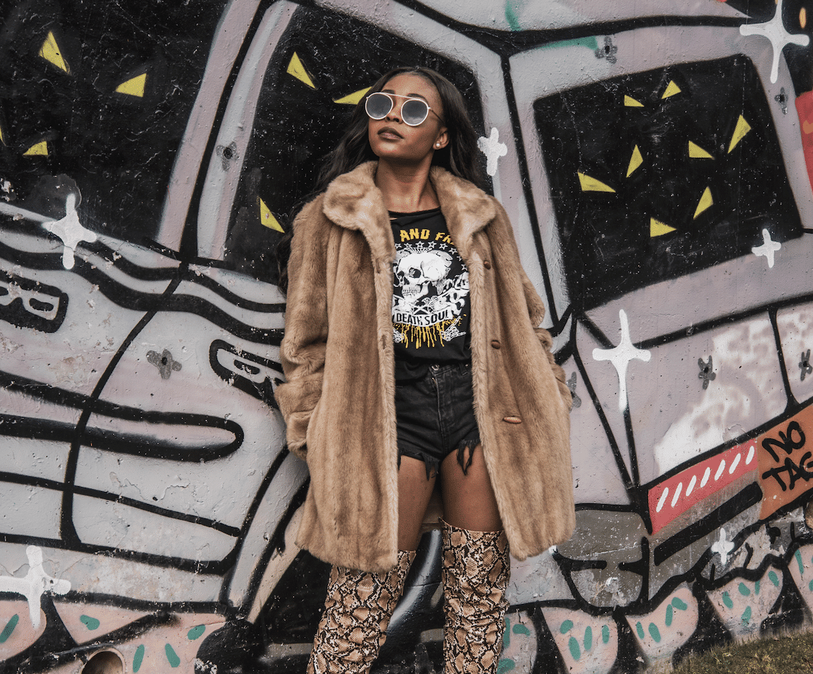 A woman wearing a coat in front of a graffiti mural